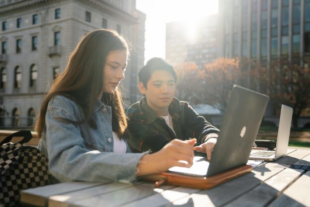 Man and Woman Sitting at Table Using Laptop